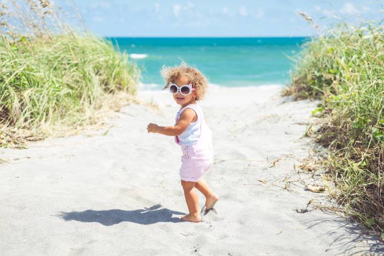 little girl walking on beach toward water